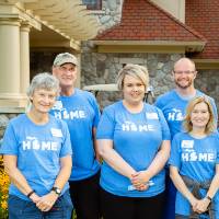 Alumni pose in front of the Alumni House